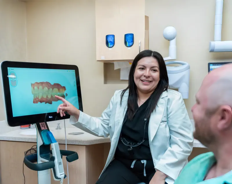 Dentist pointing to a 3D digital scan of a patient’s teeth on a chairside screen