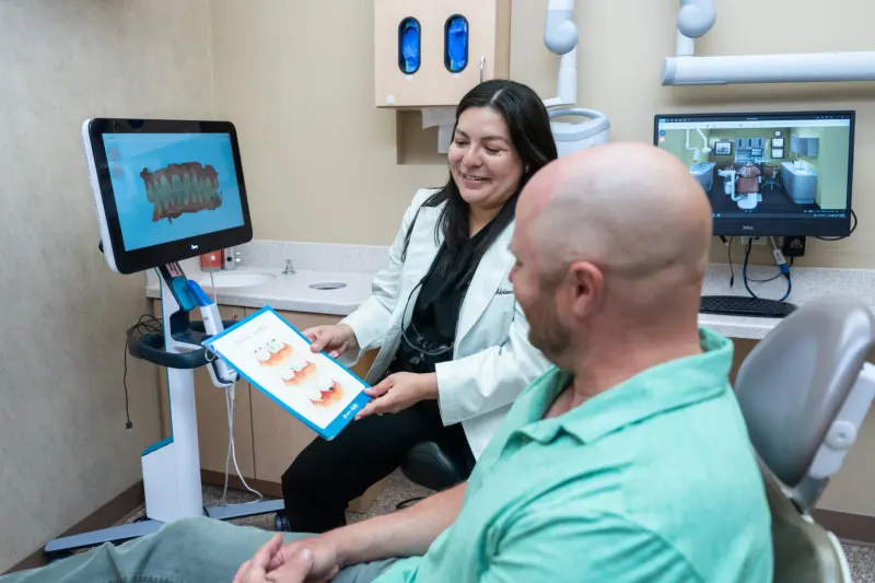 Dentist reviewing a printed treatment plan with a patient beside a digital scanner
